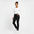 Woman wearing a white long-sleeve top and black jeans on a white background