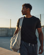 Man holding a bag on a beach at sunset