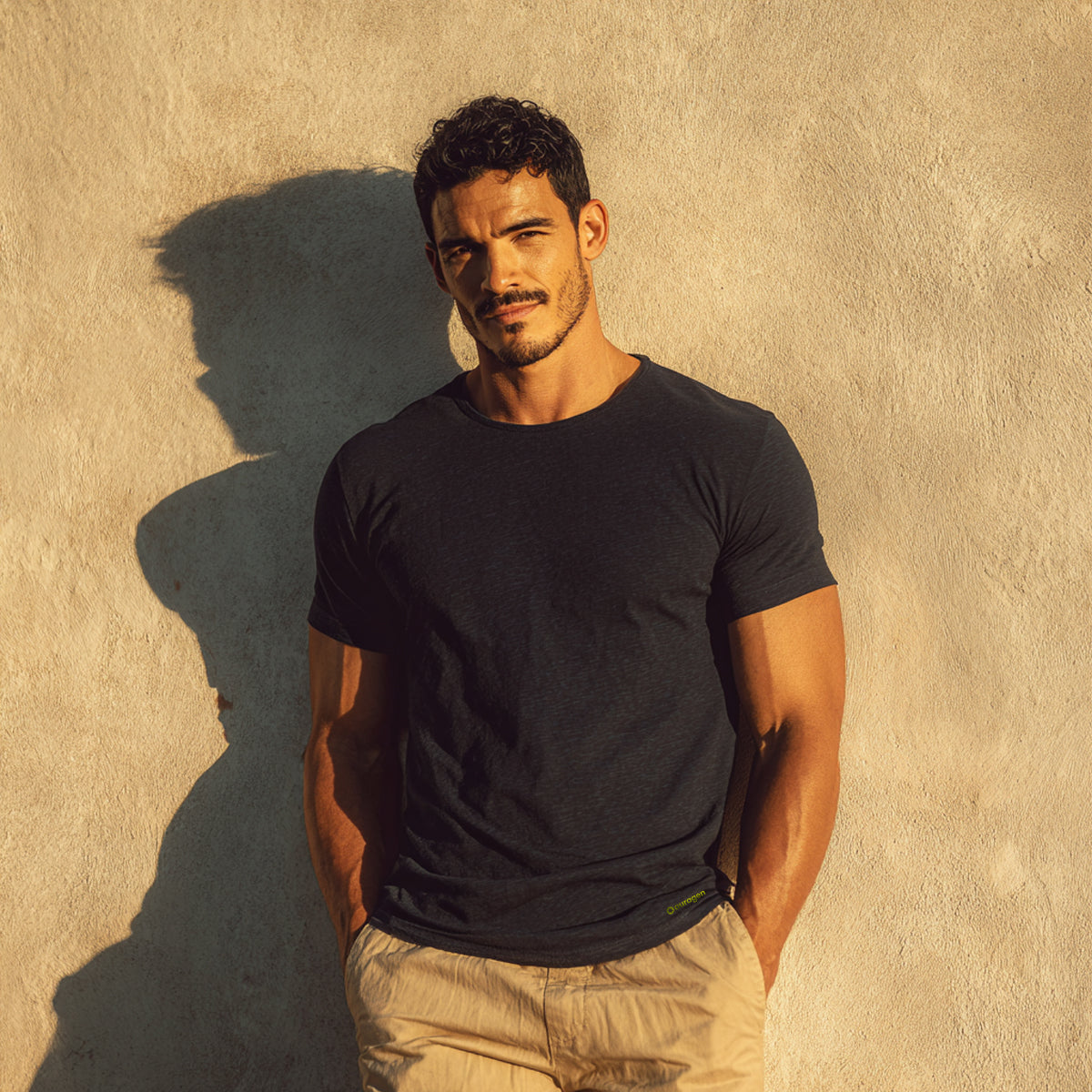 Man wearing a black t-shirt against a beige wall