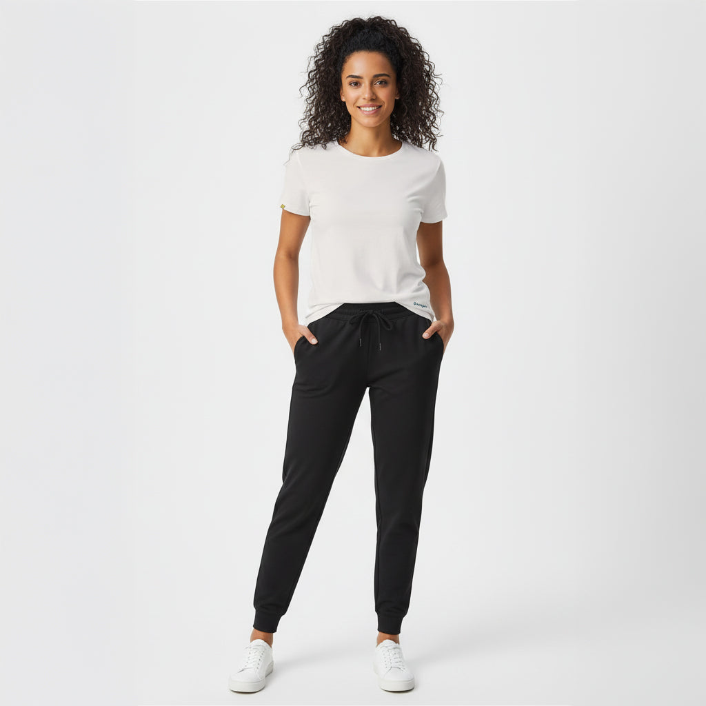 Woman wearing a white t-shirt and black jogger pants on a white background