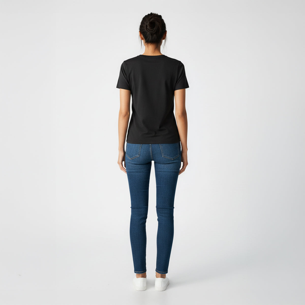 Person wearing a black t-shirt and blue jeans on a white background