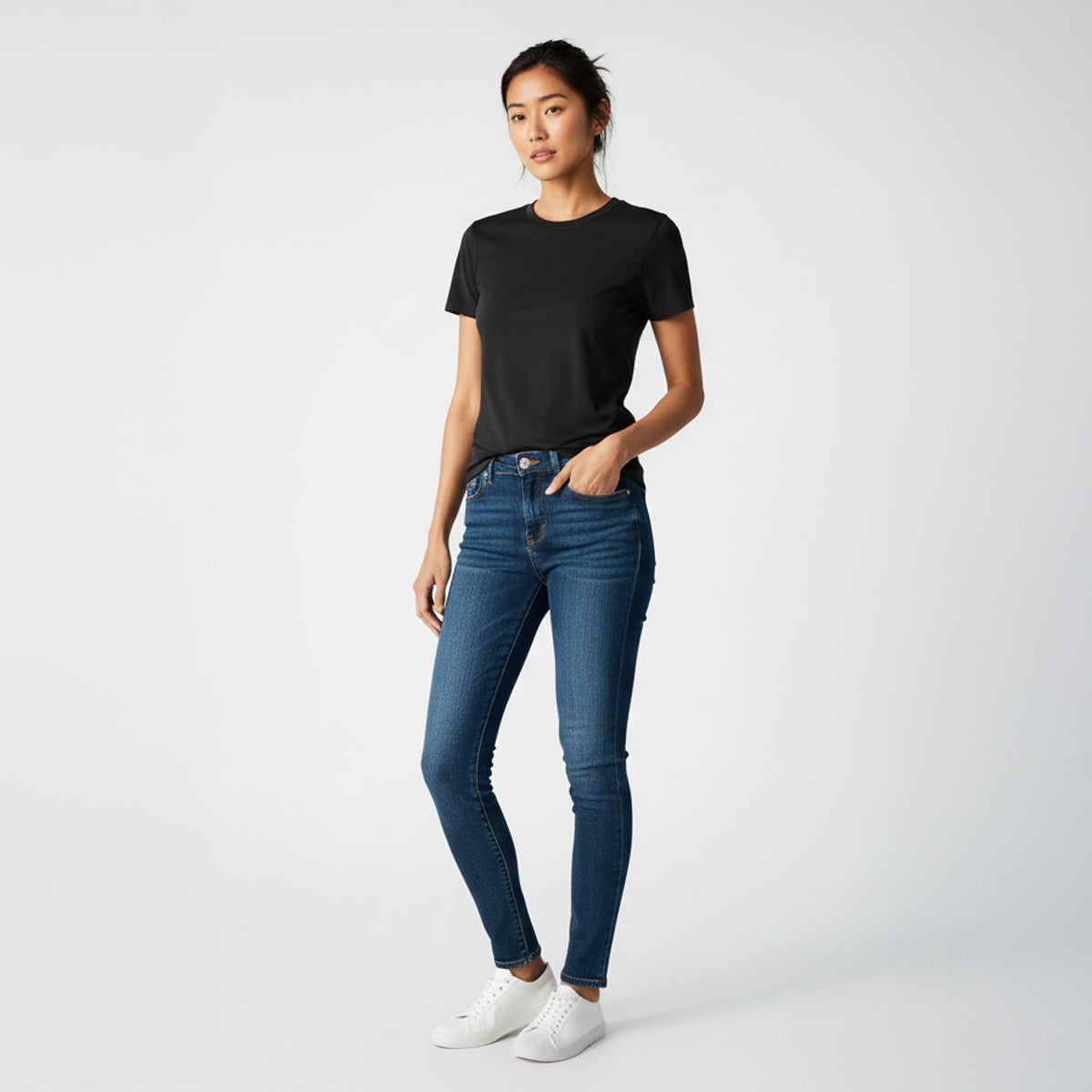 Woman wearing a black t-shirt and blue jeans on a white background
